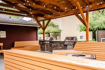 a covered outdoor entertaining area with a grill and wooden benches